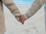 To personer holder hånd på en strand stående